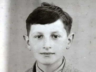 Schwarz-Weiß-Foto: Portrait von einem dunkelhaarigen Jungen. Er schaut freundlich in die Kamera.