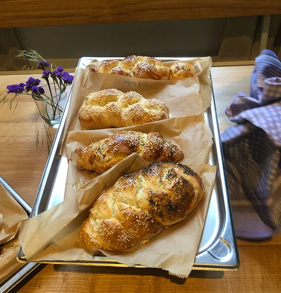 Ein Backblech mit vier Hefezöpfen, die mit Sesam und Mohn bestreut sind.