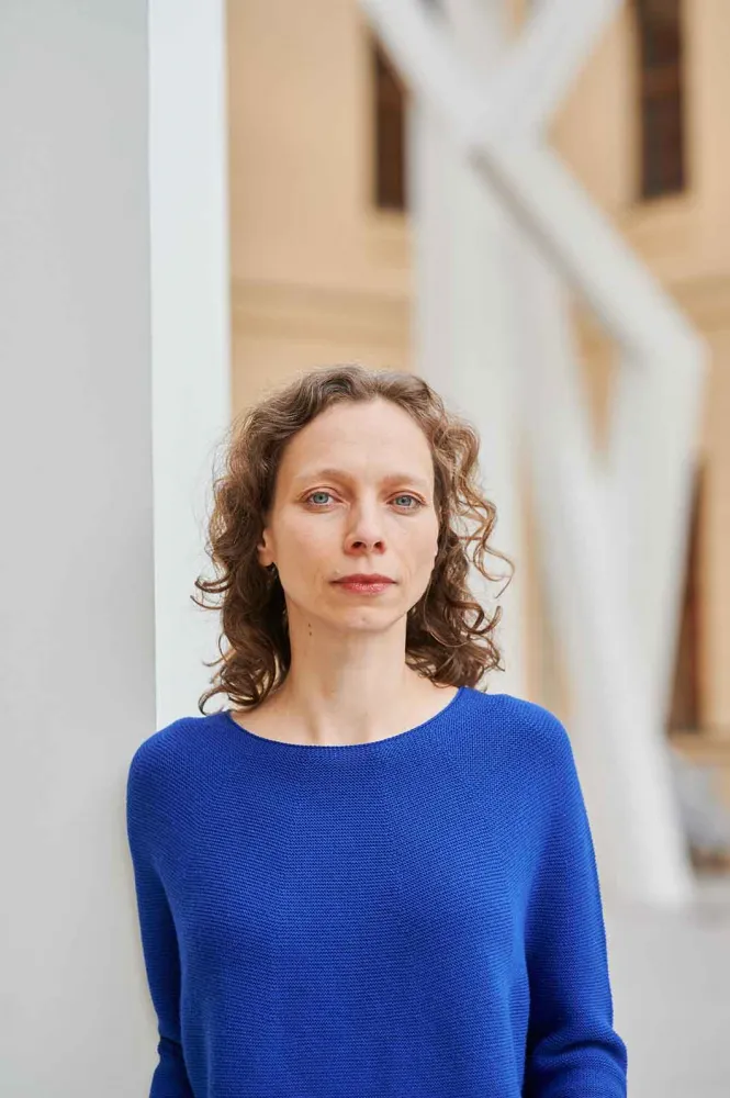 Porträtfoto einer Frau, die einen leuchtend blauen Pullover trägt: Sie schaut direkt in die Kamera.