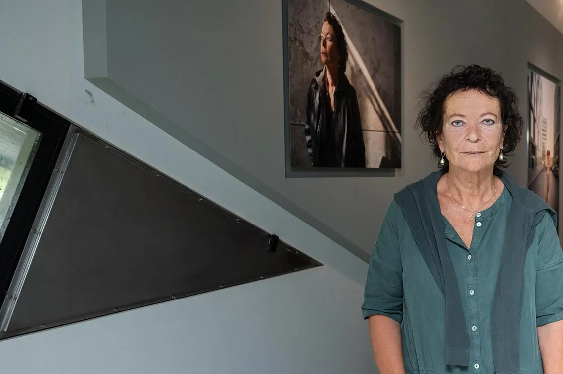 Judith Kessler vor ihrem Porträt in der Ausstellung ZERHEILT, man sieht ein Fenster des Libeskind-Baus