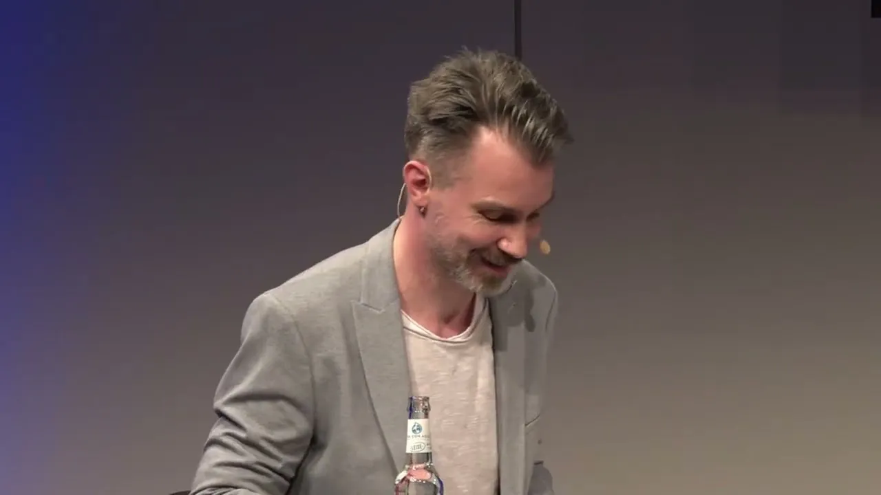 Ein Mann auf einer Bühne hinter einem Pult hält eine Rede.