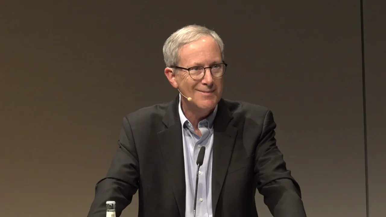 Man in suit at a lectern.